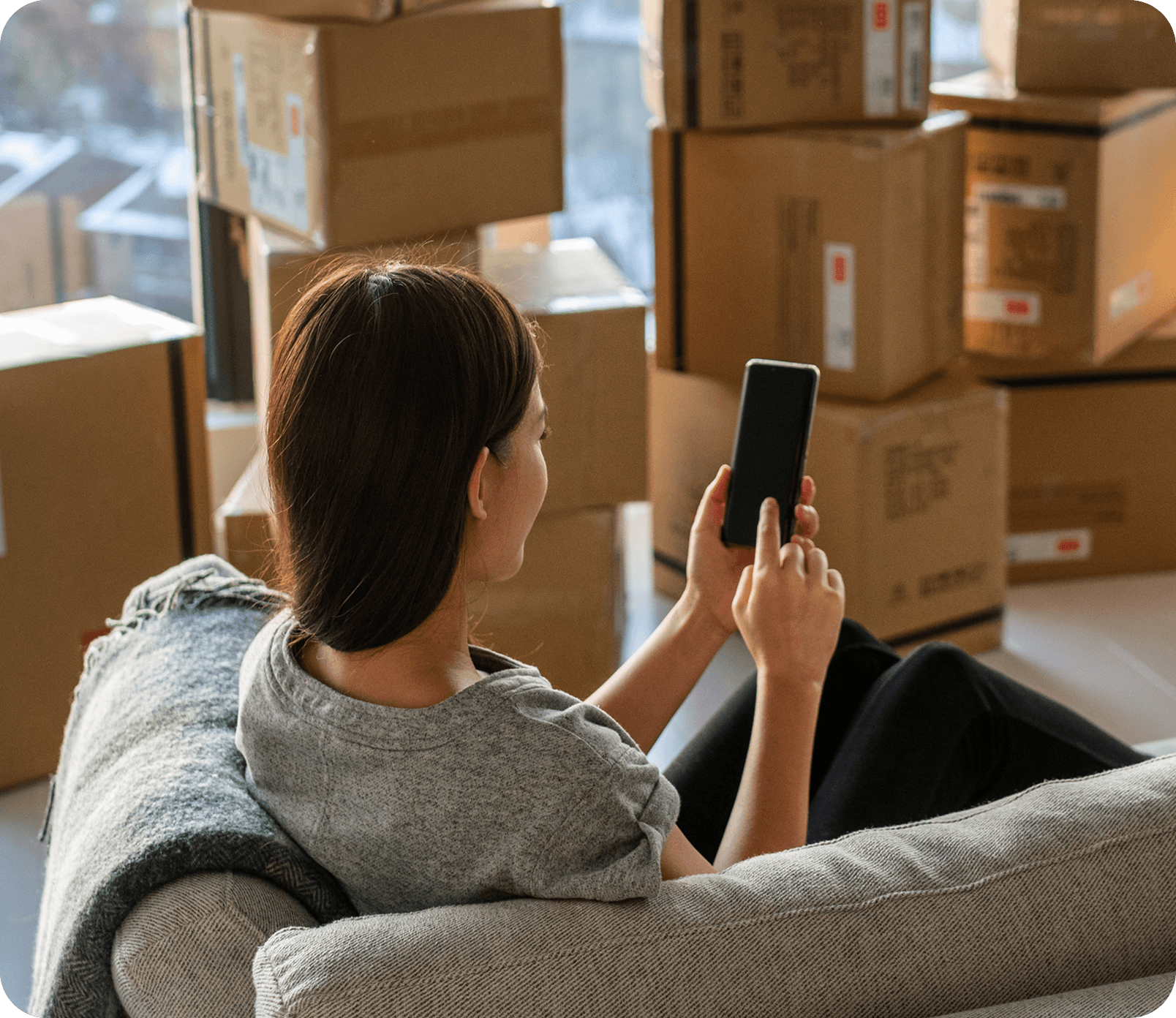 Person sitting on a couch with packed boxes around them